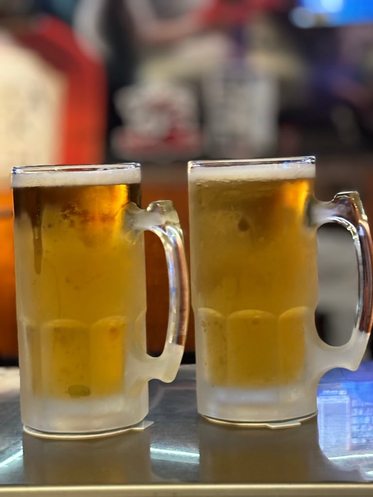 Two frosted glass mugs filled with golden beer and topped with foam